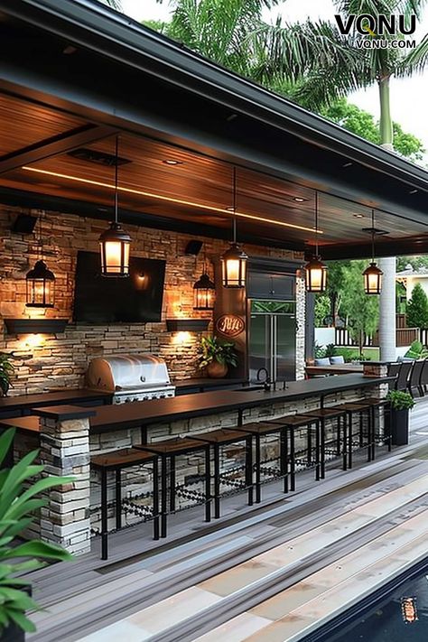 A sleek outdoor kitchen with a stone bar, lantern lighting, and a built-in grill. The design is perfect for stylish entertaining, offering functionality and a warm, inviting atmosphere. Outdoor Kitchen Pool Area, Outdoor Stone Bar, Outdoor Kitchen And Bar, Kitchen With Stone, Beautiful Houses Exterior, Neutral Bedroom Design, Backyard Creations, Lantern Lighting, Family Compound