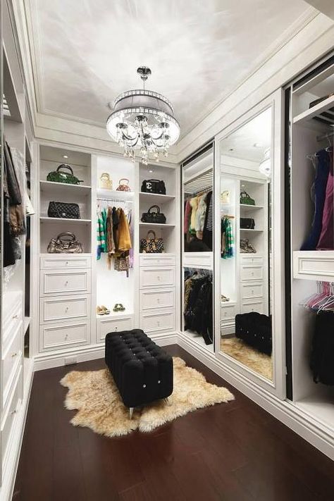 Chic walk in closet features a crystal droplets chandelier illuminating a black tufted bench on lucite legs atop a brown sheepskin pelt layered over wood floors. A Walk In Closet, Amazing Closets, Closet Vanity, Dressing Room Closet, Beautiful Closets, Dream Closet Design, Walk In Closet Design, Walking Closet, Closet Decor