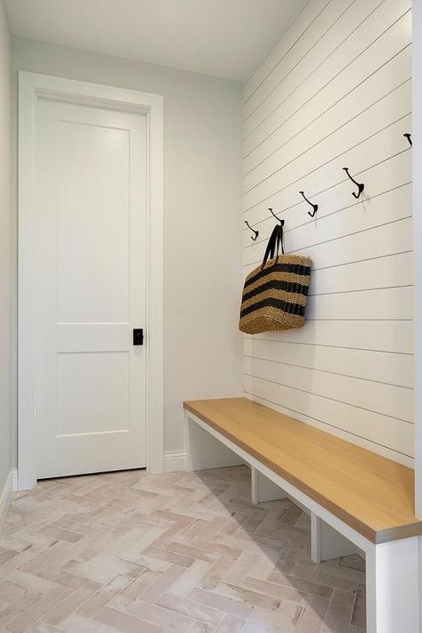 Mudroom features faded hooks on a white shiplap wall above an oak bench with open cubby style storage underneath. Vertical Shiplap Mudroom Bench, Shiplap Entryway With Hooks, Shiplap Mudroom Wall With Hooks, Entry Way With Bench And Hooks, Mudroom Coat Hooks, Shiplap Wall With Hooks, Entryway Bench And Hooks, Shiplap Mudroom, Mudroom Wall Hooks