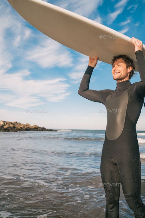 Young surfer holding up his surfboard. by megostudio. Portrait of young surfer at the beach holding up his surfboard and wearing a black surfing suit. Sport and water spor... #Sponsored #megostudio, #Portrait, #young, #surfboard Surfing Suit, Surf Culture, Vintage Graphic Design, Surfing Waves, Design Website, Sports Activities, Theme Design, Pose Reference, At The Beach