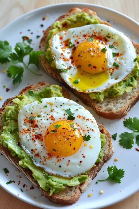 Two slices of avocado toast topped with fried eggs and a sprinkle of red seasoning, garnished with fresh cilantro leaves on a white plate. Healthy Food Fruit, Healthy Vegetarian Recipes Breakfast, Toast For Breakfast, Breakfast Ideas Avocado, Easy Breakfast Toast Ideas, Toast And Avocado, Healthy Breakfast Avocado Toast, Healthy Food Breakfast Mornings, Food Avocado