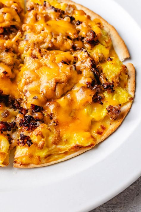 Enjoy a protein-packed start to your day with this delicious Breakfast Pizza Recipe. Featuring low-carb tortillas as our pizza crust, a cheesy, creamy sauce, scrambled eggs, crumbled sausage, shredded cheese, and any extra toppings you desire. High Protein Breakfast Pizza, Tortilla Breakfast Pizza, Egg Pizza Breakfast, Breakfast Pizzas, Breakfast Eggs Scrambled, Egg Pizza, Protein Pizza, Breakfast Pizza Recipe, Tortilla Shells