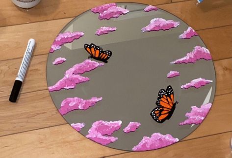 This is a round mirror with a beautiful painting of pink clouds and orange butterflies. It is 35.56cm x 35.56cm x 0.38cm. It is made with acrylic paint and can be cleaned with Windex! Order yours today. [DOES NOT COME WITH HANGING PIECE ON BACK] Cloud Painting On Mirror, Round Mirror Painting, Diy Mirror Painting Ideas, Diy Round Mirror, Mirror Painting Ideas, Spiegel Diy, Painted Mirror Art, Orange Butterflies, Cloud Mirror