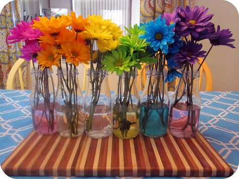 I love doing this with flowers!  You put food coloring in the water and the stem of the flower soaks it up and changes the color of the flower.  ~T Colorful Flower Centerpieces For Party, Flower Power Centerpieces, Rainbow Table Decorations, Rainbow Flower Arrangement, Color Party Ideas, Color Party Decorations, Color Party Ideas For Adults, Flower Rainbow, Flowers Simple