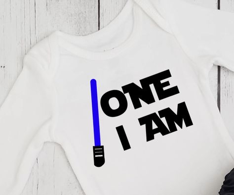 Boys 1st birthday shirt in Star Wars theme. One I am and light saber in your color choice. Custom designs available. One With The Force Birthday Party, The Force Is Strong With This One 1st Birthday, Star Wars 1st Birthday, 1st Bday Themes For Boys, Star Wars Theme Birthday, 1st Birthday Onesie, 1st Birthday Boy, Baby Birthday Themes, One Year Birthday