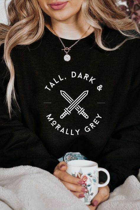 shirt that says "tall, dark, and morally grey" with swords Morally Grey Love Interest, Bookish Clothing, Book Shirt Design, Bookish Sweaters, Bookish Merch Ideas, Book Sweater, Bookish Shirt Ideas, Bookish Tshirt, Book Shirt Ideas