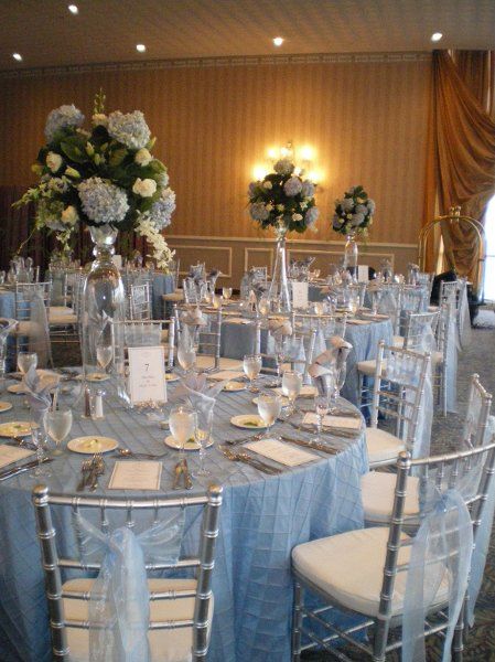 light blue wedding theme- light blue table linens, blue accents in the flower centerpieces, and light blue tulle on silver chairs Sky Blue And Silver Wedding, Blue And Silver Wedding Decorations, Blue Quinceanera Theme, Ice Blue Weddings, Baby Blue Quinceanera, Blue And Silver Wedding, Light Blue Quince, Cinderella Quinceanera Themes, Cinderella Wedding Theme