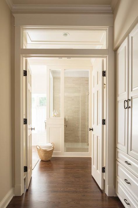 A transom window is located above white double doors opening to a master a bathroom fitted with a wood floor leading to a walk-in shower. Window Above Door, Double Door Entryway, Wood Floor Bathroom, Double Door Entrance, Small Bedroom Remodel, White Wood Floors, Cottage Bathroom, Bedroom Remodel, Transom Windows