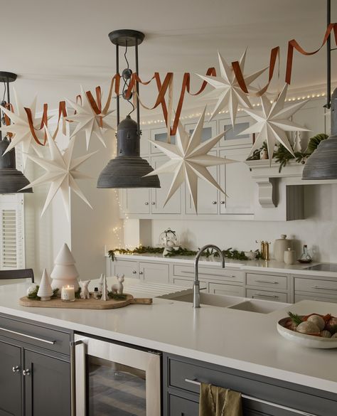 Decking out your kitchen for Christmas can be tricky. Grab some paper stars, fishing twine and command hooks, and let them stars dangle gracefully from the ceiling. Placing some fairy lights around the top of the room can also add a touch of easy magic. #christmas #christmaskitcehn #christmashome #layerdlounge Christmas Minimalist Decor, Christmas Ceiling Decorations, Simple Decorations, Cozy Houses, Minimalist Christmas Decor, Christmas Star Decorations, Paper Christmas Decorations, 2023 Art, Xmas Deco