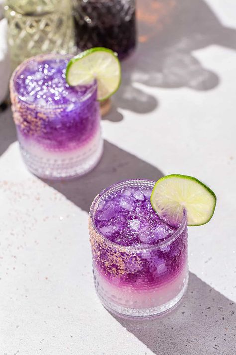 The Galaxy Margarita is as tasty as it is beautiful! Tequila that's naturally colored by butterfly pea flowers is layered on top of a Cointreau and lime base. Edible glitter takes it to the next level! It is a fun galactic spin on a classic margarita. This is the perfect margarita recipe for a girls night, bachelorette or just a night of stargazing! Perfect Margarita Recipe, Pink Gin Cocktails, Classic Tequila Cocktails, The Perfect Margarita, Prickly Pear Margarita, Butterfly Pea Flowers, Tequila Recipe, Jelly Crystals, Layered Drinks