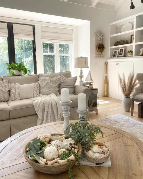 A round wood coffee table is placed on top of a soft warm rug. Warm notes of natural wood are showcased by the flooring blending seamlessly with the simple clean white tones of the cabinets and walls. An aura of comfort is exuded by the beige couch and the simple organized layout of the room...   Image: graciousspaces European Farmhouse Living Room, Ash Wood Floor, French Cottage Living Room, Country Living Rooms, Warm Rug, Beige Couch, Rustic Wood Floors, Mahogany Coffee Table, French Country Living