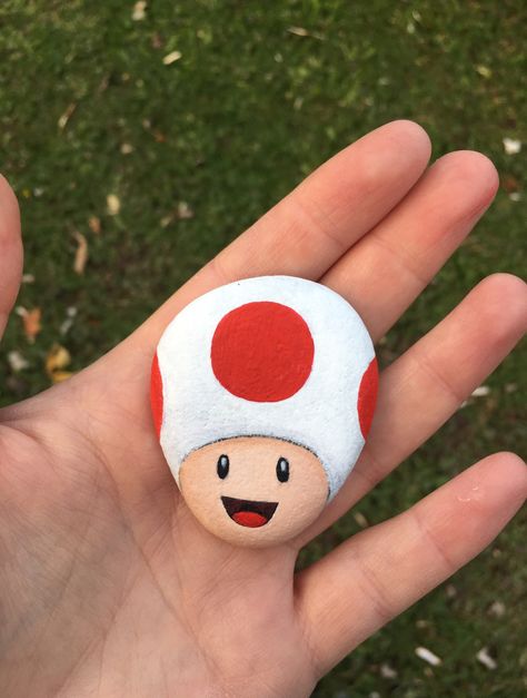 Super Mario Toad painted rock Easy Paintings On Rocks, Dinosaur Rocks Painting, Toad Rock Painting, Rock Painting Strawberry, Super Mario Rock Painting, Painted Rocks With Dots, Cute Rocks Painted Ideas, Plankton Rock Painting, Rock Painting Ideas Mario