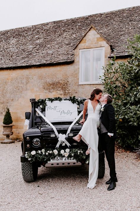 Black Landrover wedding car with white ribbon, flower bumper decorations and white welcome wedding sign with the bride and groom sharing a kiss Wedding Jeep Decorations, Wedding Vehicle Ideas, Wedding Vehicle Decorations, Decorate Wedding Car, Range Rover Wedding Car Decor, Car For Wedding Decorate, Classic Car Wedding, Wedding Fund, Bridal Car