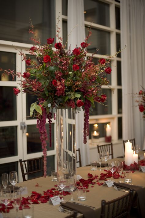 A tall centerpiece featuring red mokara orchids, burgundy james story orchids, red roses and red amaranthus.   To view our entire selection please visit us at www.starflor.com #flowers #events #eventdecor Red Amaranthus, Giraffe Hotel, Red Wedding Centerpieces, Derby Gala, Mokara Orchids, Willow Flower, Red Gold Wedding, Unique Wedding Centerpieces, Gala Decorations