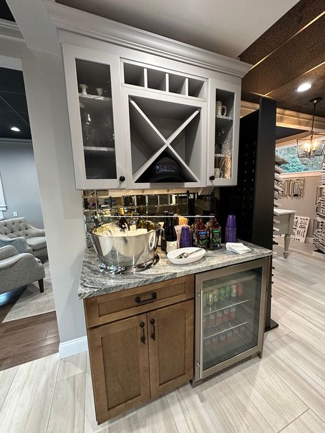 Whether you love cocktails or coffee, a dedicated serving area is a great addition to your new kitchen and entertaining space. Create a morning cappuccino bar to make guests feel welcomed, or liven up a dinner party with a self-serve drinks station. What makes this bar so awesome?  	 #KitchenCabinetry #HomeBar #CoffeeBar #DesignInspo #DreamKitchen #KitchenDesigners #HomeDesign #EmilysInteriors #ShrewsburyMA Wet Bar Ideas With Sink Coffee Stations, Back Bar With Center Mirror, Small Wet Bar With Sink Cabinets, Antique Mirror Behind Wetbar, Rustic Wet Bar Ideas With Sink, Wet Bar Designs, Self Serve, Drink Station, Bar Areas