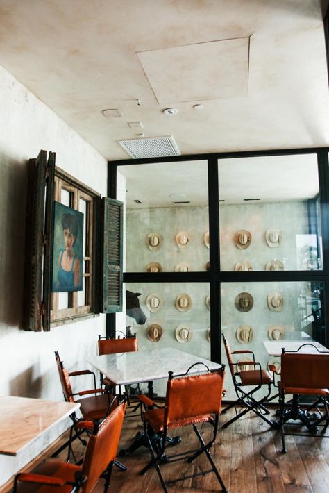 This dining area in Bracero Cocina de Raiz features a wall of steel-framed windows that showcases a view of the staircase. The staircase boasts one of the restaurant's most notable displays, an installation of vintage Bracero hats. Cowboy Restaurant, Cowboy Hat Display, Modern Cowboy, Hat Wall, Hat Display, The Staircase, Vintage Display, Wood Dresser, River House