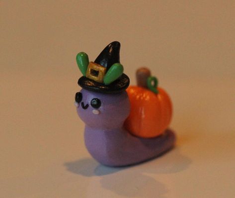 Handmade clay snail with pumpkin on its back. Snail is a light purple color and has  a witch hat on. All pieces are handmade and my differ slightly from the picture. Clay Date Ideas Halloween, Air Dry Clay Snail, Polymer Clay Snails, Halloween Clay Figures, Polymer Clay Halloween Ideas, Snail Pumpkin, Fall Clay Ideas, Jamie Core, Halloween Clay Ideas