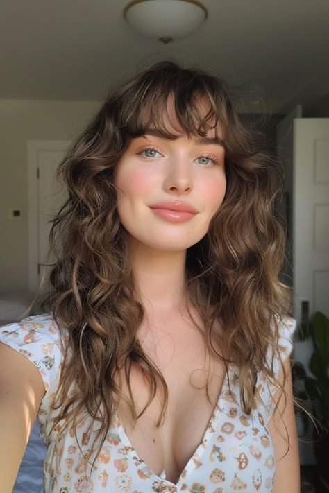 Woman with wavy hair smiling, wearing a patterned top, standing in a well-lit room. Curly Brown Hair With Curtain Bangs, Fringe Hairstyles Wavy Hair, Curly Brown Hair With Bangs, Wavy Bangs Medium Hair, Curly Layers With Bangs, Curly Wispy Bangs, Fringe Wavy Hair, Curly Fringe Hairstyles, Curly Hair With Fringe Bangs