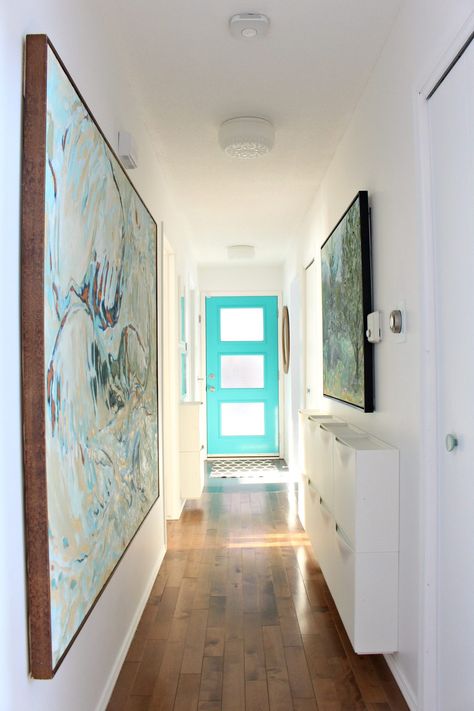 Colorful but small entryway with turquoise mid-century modern style front door, bold and large scale artwork, and a genius narrow entryway storage solution: 10 IKEA TRONES shoe cabinets, which are a shallow storage cabinet that are used in this hallways for storing dog leashes, hats, mitts and scarves. #trones #storage #smallspacestorage Narrow Entryway Storage, Shallow Storage Cabinet, Trones Ikea, Colorful Entryway, Entryway Storage Ideas, Ikea Trones, House Entryway, Aqua Inspiration, Turquoise Door