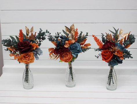 Elevate your event with these stunning autumn-inspired centerpieces! 🌿✨ #centetpieces #tabledecor #tableflowers #tealwedding #burgundywedding #artificialflowers #fauxflowerarrangement #artificialflowers #weddindflorist #weddingvendor #fallwedding Rust And Teal Wedding Colors, Dark Teal And Rust Orange Wedding Table Decor, Wedding Table Decor Without Flowers, Navy And Burnt Orange Wedding Decor, Fall Wedding Bouquets November, Rust And Navy Blue Wedding, Pumpkin Wedding Centerpieces, Homecoming Bouquet Ideas, Navy Blue And Terracotta Wedding