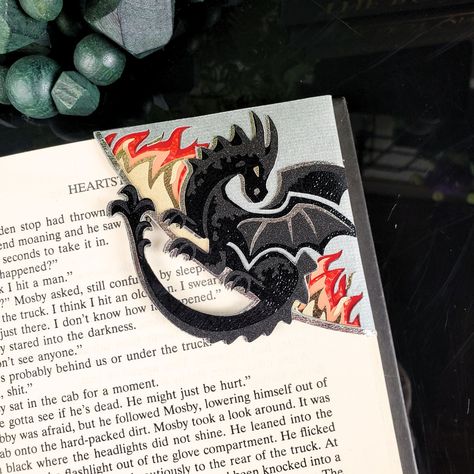 Introducing our Black Dragon Paper Corner Bookmark, a must-have for book lovers and fantasy enthusiasts. The intricate black dragon design, crafted with sparkling flames, will transport you to a world of magic and wonder every time you read. Elevate your reading experience with this luxurious and exclusive bookmark. Made with a combination of printed and textured cardstock and gold metallic vinyl for added shine. *Please note - due to the spacing on this design, we cannot add a name to this book Bookmark Corner Ideas, Diy Dragon Bookmark, Book Mark Holder, Mens Bookmark, Book Mark Handmade, Cool Bookmark Ideas, Fancy Bookmarks, Felt Bookmarks Diy, Dragon Paper