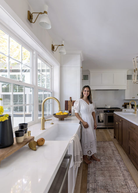 ''In this kitchen renovation, Principal Designer Natalia Avalos has infused every detail with beauty. We appreciate the neutral elegance achieved through white cabinetry and quartz countertops, harmonizing with the walnut island, and the exquisite use of brass on hardware, plumbing fixtures, window sconces, and statement pendant lights. Timeless and aesthetic, this kitchen is a true masterpiece.'' Kitchen With Windows No Upper Cabinets, Sconces Over Kitchen Window, No Upper Cabinets, Kitchen Sink Window, Kitchen Window Sill, White Cabinetry, Kitchen Window, Upper Cabinets, Plumbing Fixtures