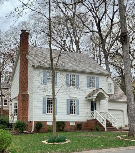 A home features SW Oyster White siding with red brick foundation. Explore all our favorite white paint colors that go with red brick in our ultimate guide. Sw Oyster White Exterior, Oyster White Exterior, Oyster White Exterior House, Sw Oyster White, White Exterior Paint Colors, Door Shutters, White Farmhouse Exterior, Exterior Paint Schemes, White Exterior Paint