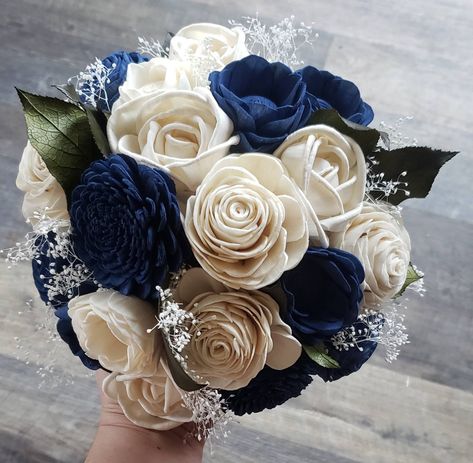 This beautiful bouquet features dark blue and ivory (raw) sola wood flowers. Accented by preserved greenery and babies breath. Pictured bouquet is 7 inches in diameter. To purchase matching boutonnieres, look here: https://www.etsy.com/shop/mydinosaurdreams/?section_id=21264911 To purchase matching corsages, look here: https://www.etsy.com/shop/mydinosaurdreams/?section_id=21264913 **Sola Flowers** *Sola flowers are hand-made from a soft wood (similar to balsa) and as such, each is unique! They Dark Blue Wedding Theme Flowers, Navy Blue And Champagne Bouquet, Midnight Blue Bouquet, Royal Blue And White Wedding Flowers, Sweet 16 Dark Blue Dress, Dark Blue Flower Arrangements, Navy Blue Quince Court, Dark Blue Quince Bouquet, Navy Blue Quince Bouquet