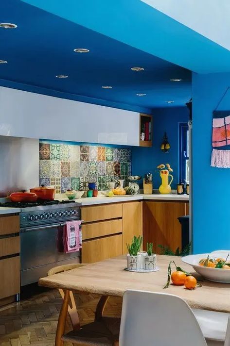 a colorful maximalist kitchen with bold blue walls and a ceiling, white and stained cabinets, white countertops and a colorful backsplash Blue And Orange Kitchen, Bright Blue Kitchen, Maximalist Kitchen, Blue Kitchen Walls, Stained Cabinets, Eclectic Kitchen Decor, Colorful Maximalist, Colorful Backsplash, Cabinets White