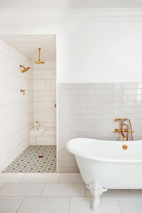 A white clawfoot bathtub sits in front of a wall half covered in horizontal gray backsplash tiles and is positioned outside of a walk-in shower. Walk In Shower And Clawfoot Tub, Bathtub In Front Of Shower Wall, Clawfoot Tub And Walk In Shower Bathroom, Clawfoot Tub Bathroom Tile Wall, Tub In Front Of Shower Wall, Small Master Bath With Clawfoot Tub, Gold Bathrooms, Hexagon Shower Floor, White Clawfoot Tub