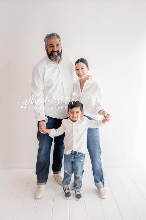 parents pose with four year old son wearing matching jeans and white button down shirt during simple studio family portraits with Saratoga Springs NY family photographer Nicole Starr Photography Photoshoot Family Of 3, White Backdrop Family Photoshoot, Family Of 3 Poses Toddlers, Family Photoshoot White Background, White And Denim Family Pictures Studio, White Studio Family Photoshoot, White Backdrop Studio Family Photoshoot, Family Of 3 Photoshoot Older Child, Studio Family Portraits