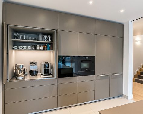 The tall bank of units has been specified and produced to fit perfectly across the wall space, from edge to edge. A shadow gap above is a nice design touch and ensures airflow around the appliances, allowing them to function correctly. A bulthaup b3 pocket door provides a useful space for small appliances and refreshment making items away from the main kitchen area. Above the main cupboard space, top box units take the cabinetry towards the ceiling, giving a wall-like appearance. Kitchen Design Decor, Kitchen Tall Units, Kitchen Unit Designs, Bulthaup Kitchen, Kitchen Wall Units, Tall Kitchen Cabinets, Kitchen Appliance Storage, Kabinet Dapur, House Design Kitchen