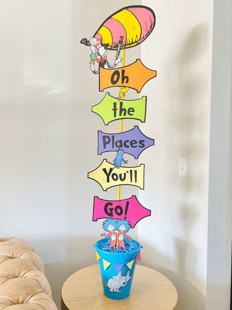 I made this for my child’s Kindergarten class Dr. Suess day. I used a Dollar Tree bucket, blue crinkle paper, 1/2” - 4ft painted dowel and colored cardstock. Dr Seuss Obstacle Course, Dr Suess Centerpieces, Dr Seuss Backdrop, Dr Suess Graduation, Dr Seuss Truffula Trees Diy, Kindy Graduation, Kindergarten Graduation Oh The Places Youll Go, Oh The Places You’ll Go Backdrop, Dr Seuss Party Decorations