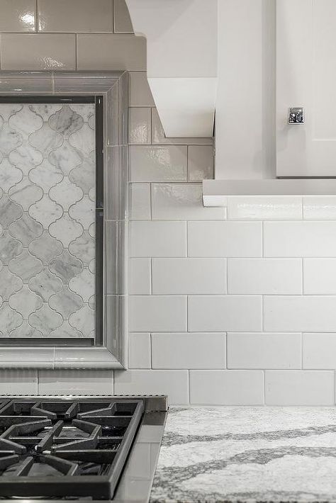 A kitchen hood with white wainscoting trim stands over a marble arabesque cooktop backsplash finished with gray border tiles and a Wolf dual range. Backsplash Accent Behind Stove, Cooktop Backsplash, Tile Inlay, Espresso Kitchen Cabinets, Subway Backsplash, White Grout, Espresso Kitchen, Stove Backsplash, White Wainscoting