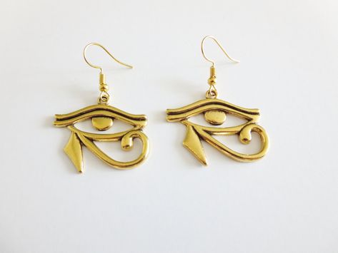 These Eye of Horus earrings are a simple way to accessory your outfit. These drop earrings are comfortable to wear and make a great gift for anyone who loves Egypt. Want 10% off? Use this link to sign up for our email list and get an instant coupon code! --> http://eepurl.com/dgRT3T Size: Earrings measure:  1 inch (drop length) Materials: Ear Wire Zinc Alloy Antique Gold Eye of Horus Charm Processing Time:  Your earrings will ship within 1-2 business days Estimated Shipping Time:  CAN: 5-7 business days  US: 5-12 business days  International: 2-4 weeks Click here to see all of our earrings: https://www.etsy.com/shop/threeyellowbeads?section_id=22707641  Follow us on social media! Instagram: instagram.com/threeyellowbeads  Pinterest: pinterest.com/threeyellowbead Facebook: facebook.com/thre Eye Of Horus Jewelry, Egyptian Design Pattern, Egypt Earrings, Eye Of Horus Wire Wrap, Unique Ankh-shaped Brass Jewelry, Egyptian Earrings Ancient, Egyptian Earrings, Egyptian Design, Eye Of Ra