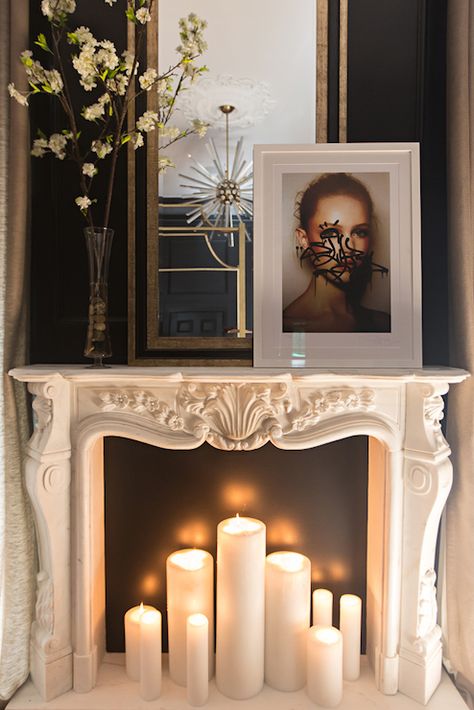 Master bedroom fireplace features an ornate carved marble fireplace mantel filled with lit candles and topped with a vase of spring blossoms, graffitied photo portrait and black and gold mirror framed by black walls. Fake Fireplace, Marble Fireplace Mantel, Glamourous Bedroom, Candles In Fireplace, The Mantle, Farmhouse Fireplace, Bedroom Fireplace, Eclectic Bedroom, Faux Fireplace