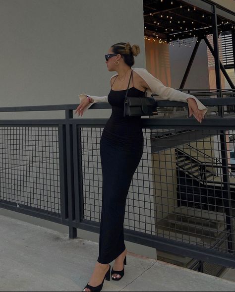 A girl is leaning against a railing with a long black, skin tight dress on. She’s  wearing black heels, a beige shrug, and a little black purse. Body Con Maxi Dress Outfit, Brunch Date Outfit Summer, Long Bodycon Dress Outfit, Black Bodycon Dress Outfit, Long Black Dress Outfit, Long Black Bodycon Dress, Tight Maxi Dress, Black Maxi Dress Outfit, Bodycon Dress Outfit