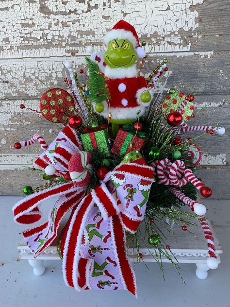 Christmas Centerpiece Christmas table centerpiece Christmas floral arrangement table decor Santa Elf This Christmas arrangement will look great as a centerpiece for your table or anywhere you want to add Christmas cheer. The arrangement is on a metal white tray with greenery, sprays, ball picks, candy picks, adorable Santa holding a tree with garland of lights and a holiday bow.  Measures approx. 16"H X 12"W SHIPPING FEE IS INCLUDED IN LISTING PRICE  Please check out my other listings and Thank you for looking! Please follow me on Pinterest" for all of my latest and past designs  Link: https://www.pinterest.com/cylesdazzlingdesigns/boards/ Please follow me on Facebook "CylesDazzlingDesigns" for all of my latest designs and/or Custom order your design. Link: https://www.facebook.com/cylesda Grinch Arrangement, Grinch Centerpiece, Tree With Garland, Grinch Diy, Centerpiece Christmas Table, Candlestick Arrangements, Table Centerpiece Christmas, Christmas Tree Village Display, Christmas Table Centerpiece