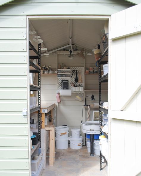 Pottery studio/shed, photographed from the door. The exterior of the shed is light green, whilst the interior is cream. In shot, you can see shelving units, a workbench, a pottery wheel and tools lining the walls. Small Ceramic Studio Ideas, She Shed Pottery Studio, Small Home Pottery Studio Setup, Small Home Pottery Studio, Pottery Organization, Outdoor Pottery Studio, Pottery Shed Ceramic Studio, Pottery Studio Shed, Tiny Pottery Studio