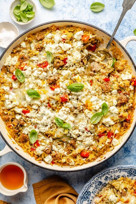 Comforting zucchini and sausage baked orzo packed with a rainbow of veggies and plenty of melty cheese. This one pan sausage baked orzo recipe is easy to make and customize, and is made extra delicious with a drizzle of hot honey. The perfect nourishing and cozy weeknight meal! Healthy Orzo Recipes Dinners, Zucchini And Sausage, Honey Feta, Zucchini Sausage, Baked Orzo, One Pan Sausage, Orzo Bake, Sausage Orzo, Gluten Free Orzo