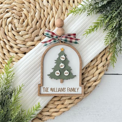 Celebrate the joy of family this holiday season with our Personalized Family Christmas Tree Ornament! Each ornament is custom-engraved with your family name at the base, and up to six family member names on the small ornaments, making it a unique and special keepsake! A thoughtful and personalized gift for friends and family, celebrating the bonds of togetherness and love, this ornament is sure to add a personal and festive touch to any Christmas tree! Each ornament is made to order and finished with a ribbon for hanging! Please be sure to add the names for personalization in the box below! (Maximum Of 6 Names) Please be sure to double check all spelling! Dimensions: Height: 4 inches Width: 3.25 inches Depth: .325 inches Check out our full collection of Christmas Ornaments here: https://ww Diy Family Christmas Ornaments, Laser Ornaments, Family Christmas Ornaments Personalized, Personalized Ornaments Family, Wooden Family Ornaments, Wood Family Ornament, Family Ornaments Personalized Cricut, Acrylic Family Ornament, Family Ornaments Personalized Handmade