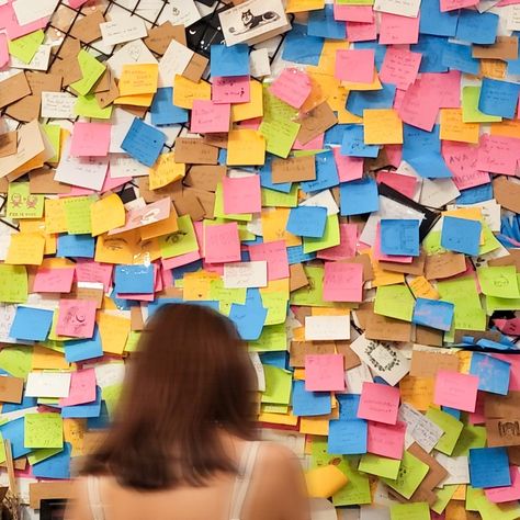 A colorful wall full of sticky notes with different drawings, a blurry girl with her back to the camera Sticky Notes Photography, Colorful Wall Collage, Sticky Note Wall, Friend Hangout Ideas, Notes Photography, Activities To Do With Friends, Friend Hangout, Wish Wall, City Activities