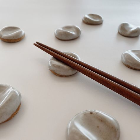 "These handmade ceramic chopstick or paintbrush rests are designed to look like a pebble or stone, adding an organic look to your table or desk. The design is simple, yet versatile, and can be used as a paintbrush rest, chopstick rest, pen holder, or even a worry stone. ☼ PRODUCT DETAILS ☼ * Each rest measures about 1.5\" round * Hand molded for an organic look * Stoneware clay * Warm off-white matte glaze with dark speckles * Food and dishwasher safe ☼ CHOPSTICKS AVAILABLE AS ADD-ON ☼ * If sele Ceramic Chopstick Holders, Diy Chopstick Rest, Air Dry Clay Chopsticks Rest, Ceramic Chopstick Rest, Chopstick Holder Ceramics, Chopstick Rest Ceramics, Clay Chopstick Rest, Clay Chopstick Holder, Ceramic Chopstick Holder