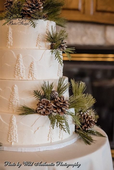 For Becky and Joshua’s outdoorsy February wedding, we topped their four-tier cake with a burst of pinecones and evergreen dusted with powdered sugar, which looks like a fresh layer of snow. Simple yet effective! The rustic motif continues down the side of the cake, which is frosted in buttercream textured to look like snow-covered mountains and trees. An elegant idea for a woodland, Christmas, or Winter Wonderland themed wedding. Photo from www.thewildauthentic.com. #spbakeshoppe Wedding Cake With Pinecones, Buttercream Texture Wedding Cake, Pine Cone Wedding Cake, Pinecone Wedding Cake, Rustic Christmas Wedding Cake, Pine Tree Wedding Cake, Elegant Winter Wedding Cake, Woodland Winter Wedding, Winter Theme Wedding Cake