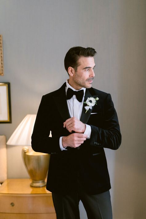 Groom prep photo posing with his black velvet tuxedo and black and white buttonhole Black Velvet Wedding Suit, Groom Classic Suit, Black Wedding Tuxedo, Black Velvet Groom Suit, Black Velvet Tuxedo, Classic Wedding Tuxedo, Black Velvet Tuxedo Wedding, Luxury Winter Tuxedo For Black-tie Events, Tailored Black Three-piece Wedding Suit