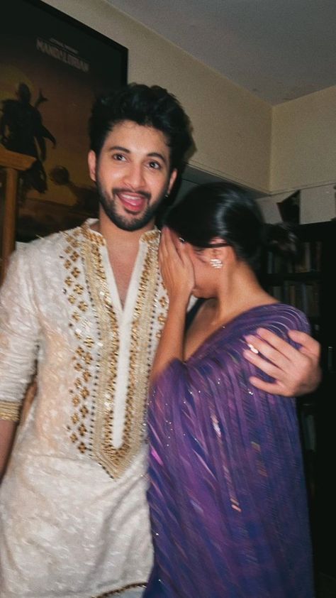 An Indian couple embraces in front of a stunning backdrop of vibrant, colorful architecture and lush greenery. The man is dressed in traditional Indian clothing, while the woman wears a beautiful saree. The warm hues of the sunset cast a golden glow over the scene, adding to the romantic and picturesque aesthetic Dating Dr Dil, Old School Romance, Indian Couple Aesthetic, Desi Love, Indian Couple, Pani Puri, Us When, Couple Picture Poses, Love Us