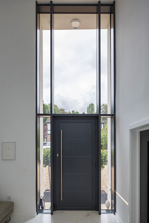 The entrance door in this Hertfordshire home makes a huge impact and is such a wonderful feature in this home. The elegant glazing above the door adds a striking and luxurious finish, whilst allowing the natural light to flood the entryway.⁠ ⁠ Having been recommended by their Architect, the client chose this @origin_global entrance door and windows for this part of the home! Get in touch if you would like to chat about the glazing for your project. Huge Doors Entrance, Big Glass Front Door, Big Glass Doors Entrance, Textured Glass Door Entrance, Glass Entry Doors Grand Entrance, Window Above Door, Huge Door, 48”luxury Front Door With Side Lights, Door Entryway