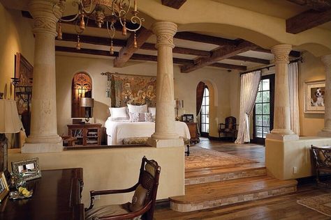 This massive bedroom actually has two levels, separated by a set of large textured columns. The floors are a rich stained hardwood. The walls are a light creme color, which matches the ceiling. There are large rafters crossing each other on the ceiling, which help to give the room some depth. The upper level features the bed and side tables, while the lower contains the working desk. Luxurious Master Bedrooms, Rustic Coastal, Sanctuary Bedroom, Casas Coloniales, Spanish Style Homes, Bedroom Floor Plans, Luxury Bedroom Master, Elegant Bedroom, Bedroom Flooring