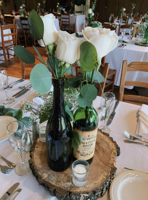 Wedding Table Decor Bottles, Wine Bottle And Wood Centerpieces, Whiskey And Wine Wedding Theme, Green Bottle Centerpieces, Alcohol Bottle Decorations Wedding, Wine Bottle Centerpiece Ideas, Vineyard Wedding Table Decor, Wine Bottle Flower Centerpiece, Wine Theme Centerpieces