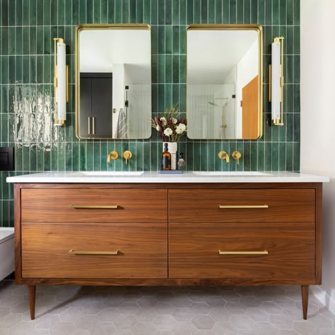 GRAFF’s Brushed 24 Karat Gold designs pop against dazzling emerald green subway tiles, and the warmth of a Mid Century Modern styled vanity give this space a trendy, sophisticated, and fun flare. Interior Design: Amy Pearson Design Photography: Meagan Larsen #interiordesign #modernbathroom #luxuryhomes #bathroominspiration #luxurybathroom #GRAFFDesigns #ArtofBath #AmyPearsonDesign #MeaganLarsenPhotography #Midcenturymodern #subwaytiles #24KGold Green Accent Wall, Green Tile Bathroom, Green Accent Walls, Mid Century Modern Bathroom, Mid Century Bathroom, Apartment Decoration, Bad Inspiration, Upstairs Bathrooms, Green Tile